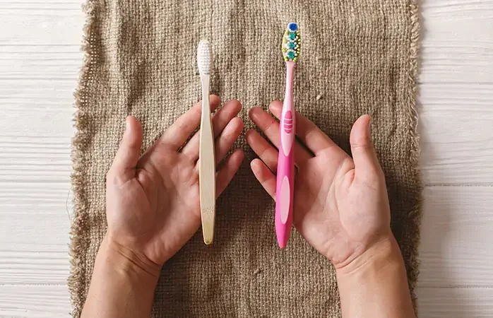 hand holding eco natural bamboo toothbrush and in other hand plastic toothbrush, flat lay on rustic background. sustainable lifestyle concept. zero waste. choice plastic free items; Shutterstock ID 1170203749; Purpose: Plastic free travel tips; Brand (KAYAK, Momondo, Any): momondo