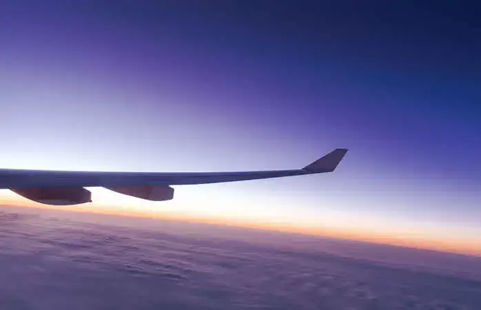 The plane flew over the clouds at sunset