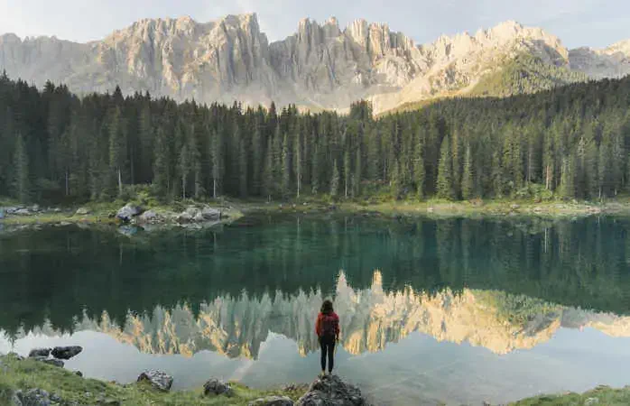 Young Caucasian woman standing and looking at Lago di Carezza in Dolomites